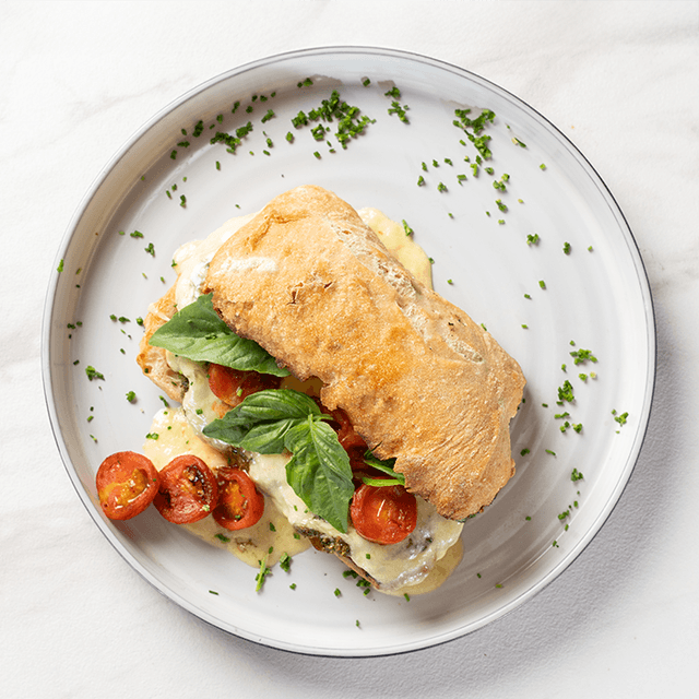 Caprese del Huerto - Queso fundido, tomates cherry asados, pesto de albahaca en pan ciabatta artesanal en Le Grenier
