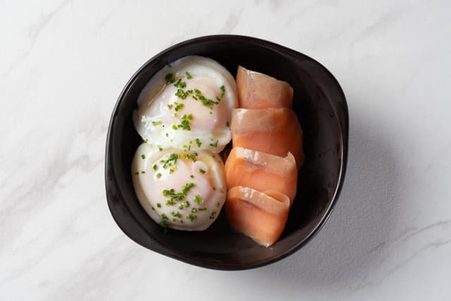 Huevos Pochados - Huevos pochados al plato con aceite de oliva y hierbas, con salmón ahumado o jamón serrano en Le Grenier