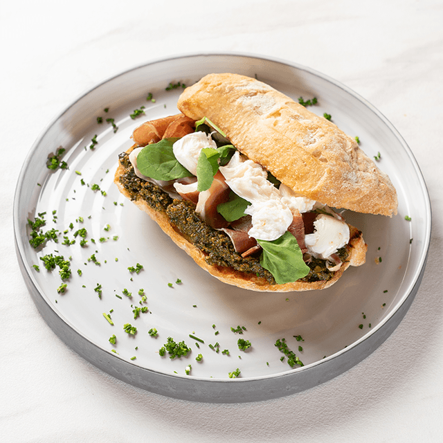 Serrano & Pesto - Jamón serrano, rúcula fresca, pesto de albahaca y queso burrata en pan ciabatta artesanal en Le Grenier