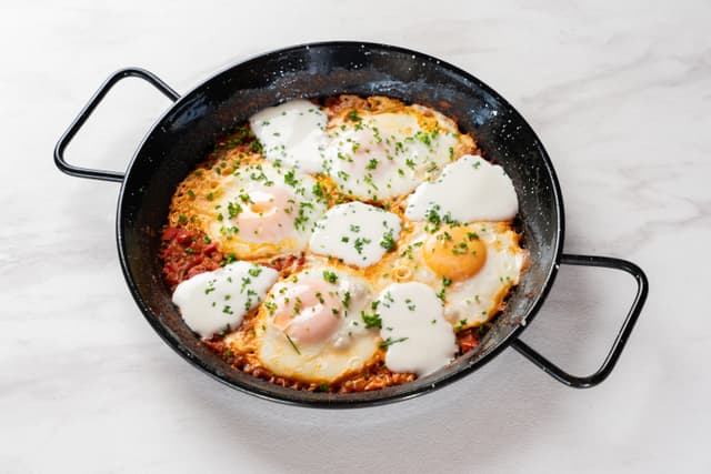 Shakshuka para 2 - Sartén al centro con 4 huevos, salsa de tomates especiada, pimentón, cebolla e hierbas frescas en Le Grenier